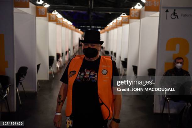 Helper greets as people arrive to receive a vaccination against the coronavirus during a long night of vaccinations with music at the Arena Treptow...