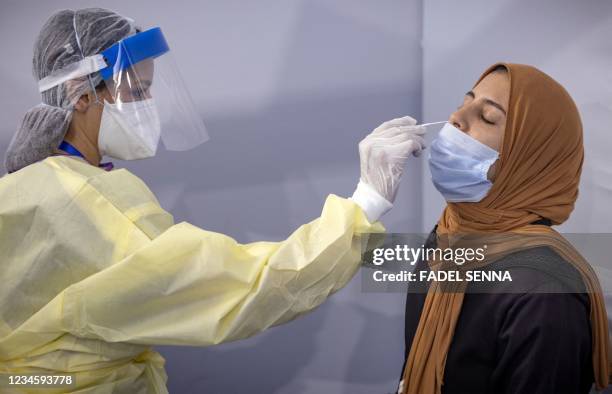 Moroccan health worker wearing protective gear collects a nasal swab for a Covid-19 express PCR test at a centre, part of the local "smart...