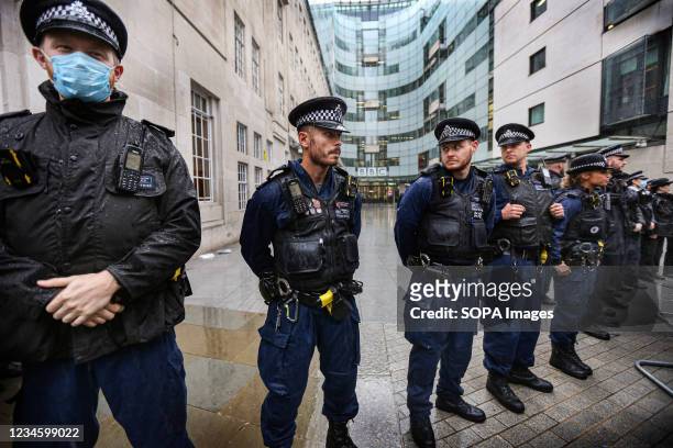 Police officers form a cordon to prevent protesters from entering the BBC building during the demonstration. Protesters held a demonstration against...