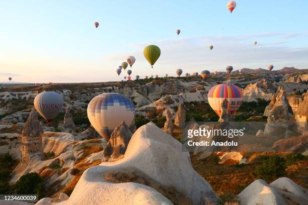 Hot air balloons glide over historical Cappadocia region, located in Nevsehir province of Turkey on August 10, 2021. A total of 138,225 tourists...