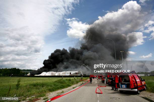 Des pompiers travaillent sur un incendie due à un accident sur un poste de travail qui a détruit 2000 mètres carré d'entrepôt, le 11 mai 2007 à Thil....