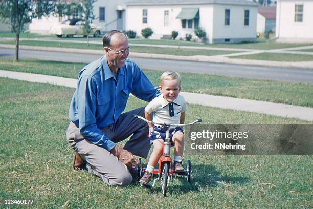 grandfather teaching grandson to ride tricycle 1953, retro - photography stock pictures, royalty-free photos & images