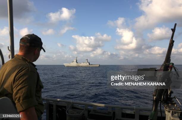 Member of the Israeli navy stands in a boat backdropped by Israeli Atzmaut warship, a Saar 6 corvette, during a welcome ceremony by the after its...