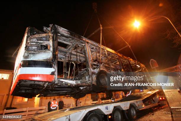 La carcasse d'un bus incendié est chargée sur la remorque d'un camion, le 03 février 2007 à Coulaines près du Mans. D'après les témoignages des deux...