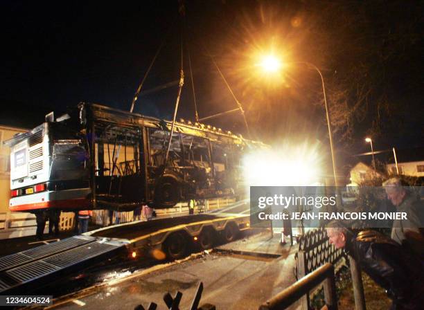 La carcasse d'un bus incendié est chargée sur la remorque d'un camion, le 03 février 2007 à Coulaines près du Mans. D'après les témoignages des deux...