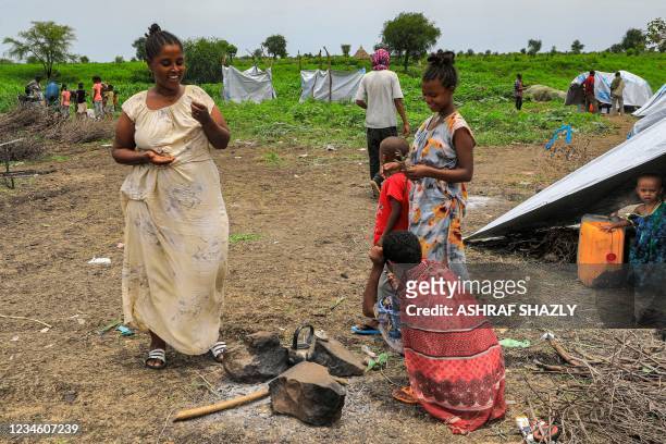 Girls stand around a sitting woman at a camp for Ethiopian refugees of the Qemant ethnic group in the village of Basinga in Basunda district of...
