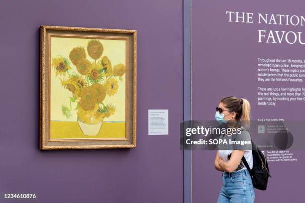 Woman in a face mask views Vincent van Gogh's paintings of Sunflowers at an outdoor pop-up gallery showcasing over 20 full sized reproductions of...