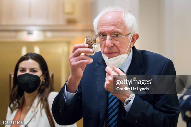 Sen. Bernie Sanders lowers his mask and holds up an ice cream sandwich while taking a break from the Senate floor budget resolution proceedings on...