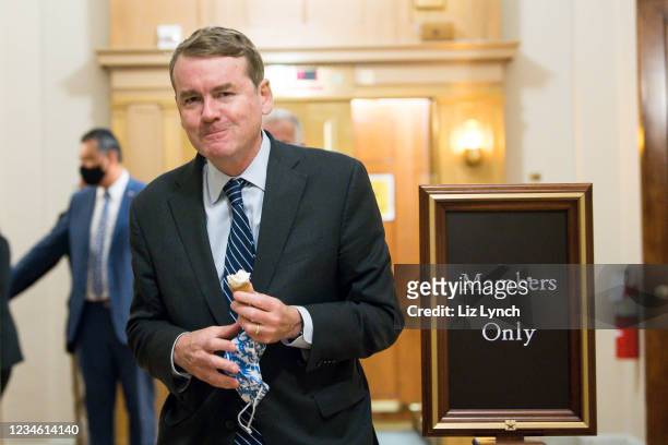 Sen. Michael Bennett eats an ice cream cone while walking in the halls of the Capitol during the budget resolution proceedings on August 10, 2021 in...