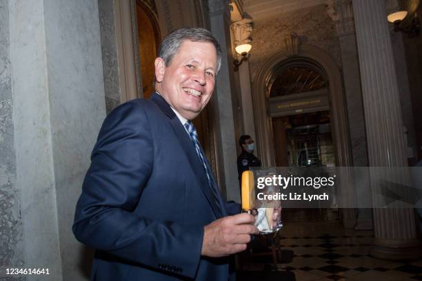 Sen. Steve Daines carries a popsicle and an ice-cream cone as he heads back to the Senate chamber on August 10, 2021 in Washington, DC. The Senate is...