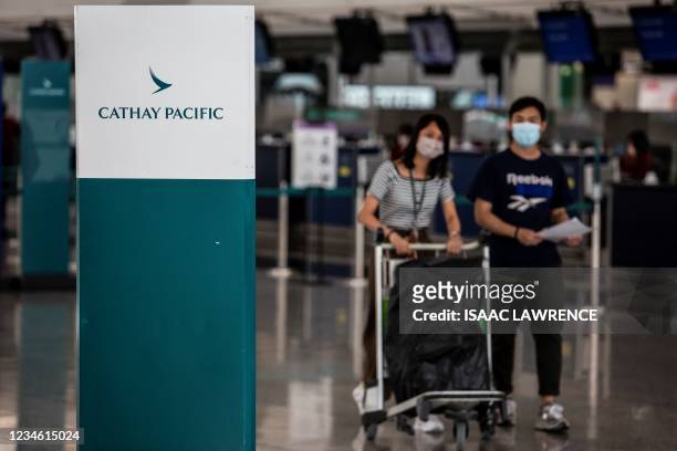 Passangers walk past the Cathay Pacific check in counters at Hong Kong International Airport on August 11, 2021.