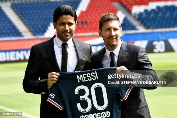 Paris Saint-Germain's Qatari President Nasser Al-Khelaifi poses along side Argentinian football player Lionel Messi as he holds-up his number 30...