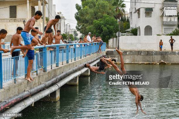 Boys jump to dive in the Mediterranean sea waters at the Kheireddine bridge near the northern Tunisian town of La Goulette about 12 kilometres east...