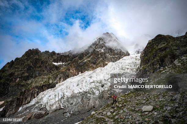 An hiker walks on the path to the Boccalatte Hut near the Planpincieux Glacier in Courmayeur, Alps Region, north-western Italy, on August 5, 2021. -...