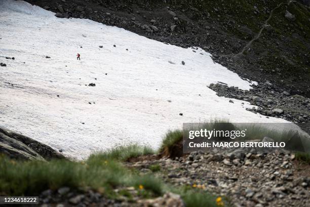 An alpinist walks on a snowfield on the path to the Boccalatte Hut in Courmayeur, Alps Region, north-western Italy, on August 5, 2021. - A melting...