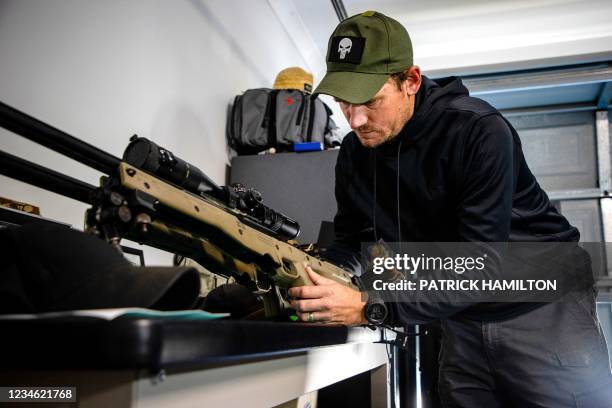 This photo taken on July 20, 2021 shows Australian Defence Force veteran James Hintz looking after a sniper rifle as he speaks about his military...