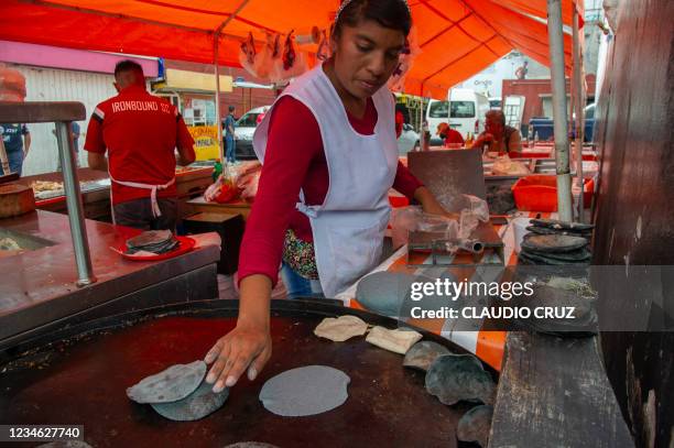 Woman prepares tortillas to sell on the street in Mexico City on August 7, 2021. - Insects and corn have been two of the staples of the Mexican...