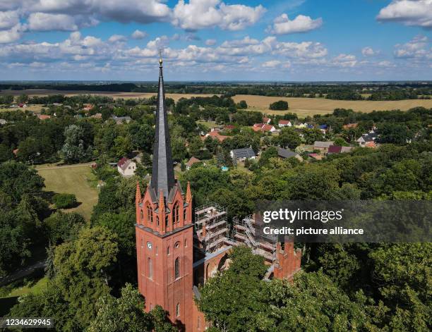 August 2021, Brandenburg, Reitwein: Between the trees at the Reitweiner Sporn, a striking wooded ridge also called Reitweiner Nase, the church of...