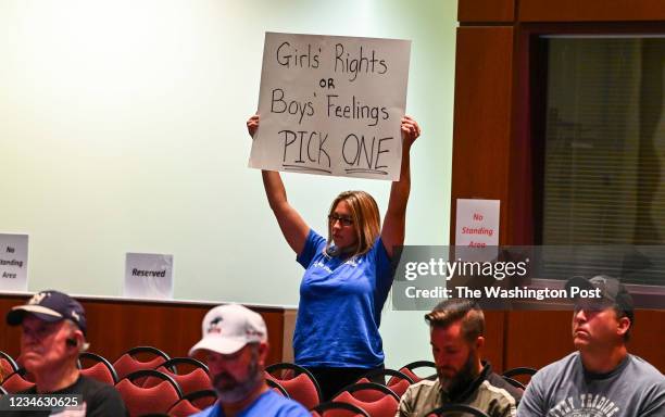 Woman holds a sign as Loudoun County School Board members vote to enact Policy 8040 during a school board meeting at the Loudoun County Public...
