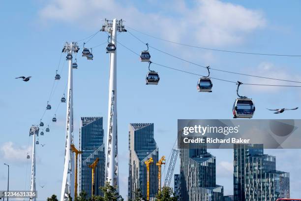 View of Emirates Air Line cable cars and Thames riverside residential apartment high-rises on the Greenwich Peninsular, on 11th August 2021, in...