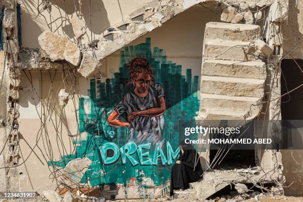 Woman sits along the broken steps of a partially-collapsed building destroyed by bombardment during the May 2021 confliict between Hamas and Israel,...