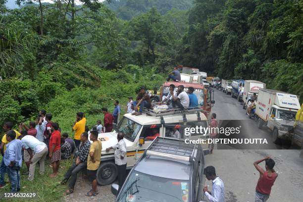 Stranded people stand near the site of a landslide along the national highway that connects Sikkim and West Bengal states, in Sevok on August 12,...