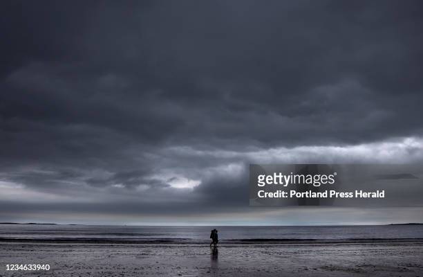 Couple walks along the beach on Monday afternoon under ominous skies.