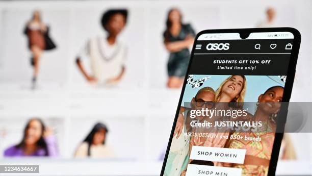 An illustration with a laptop and mobile phone shows the website of online fashion retailer ASOS on August 12, 2021.