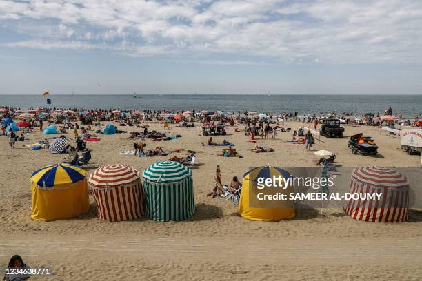 Vacationers stand on the beach in Trouville-sur-Mer on August 12, 2021.