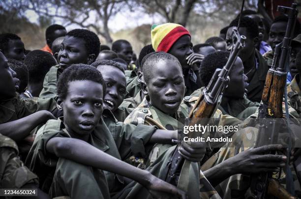 Young boys, children soldiers sit on February 10, 2015 with their rifles at a ceremony of the child soldiers disarmament, demobilization and...