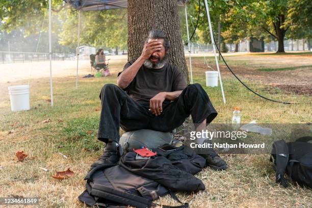 Homeless man who asked to not be named tries to stay cool near a misting station in Lents Park during an extreme heat wave in August 13, 2021 in...