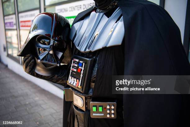 August 2021, North Rhine-Westphalia, Duisburg: A "Darth Vader" costumed from the Star Wars film series holds his helmet in his hand. Duisburg...