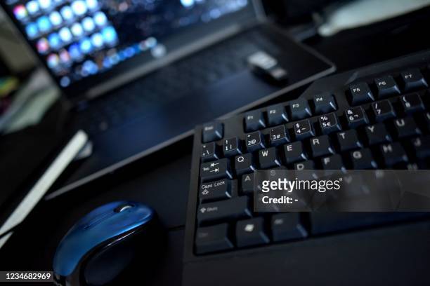 This photo illustration taken on August 13, 2021 shows a home office desk with a keyboard, a mouse and a laptop in Los Angeles, California. - In the...