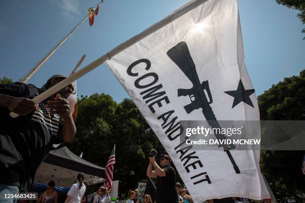 Man waves a a "Come and Take It" flag in support of military-style semi-automatic weapon ownership during an anti-vaccination protest rally near City...