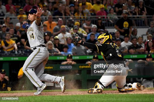Jace Peterson of the Milwaukee Brewers reacts as he slides in safely past Michael Perez of the Pittsburgh Pirates to score a run in the sixth inning...