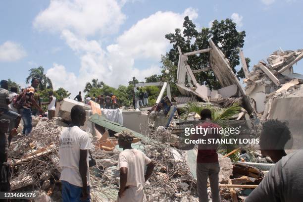 People search through the rubble of what used to be the Manguier Hotel after the earthquake hit on August 14, 2021 in Les Cayes, southwest Haiti. -...