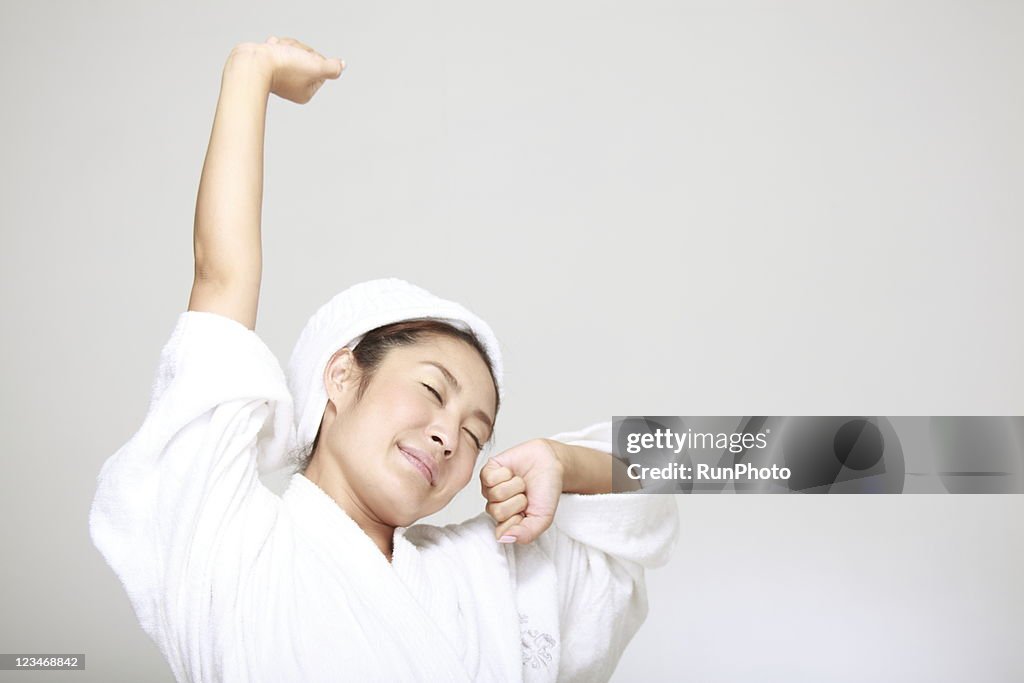 Young woman stretching in bathrobe