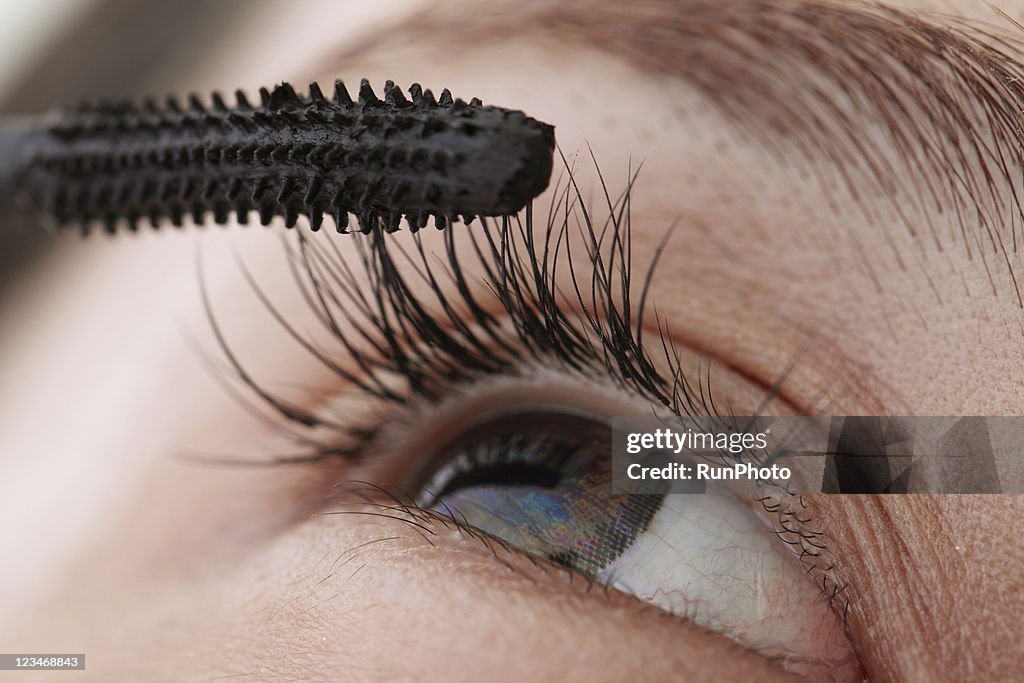 Young woman applying mascara,close-up,beauty care
