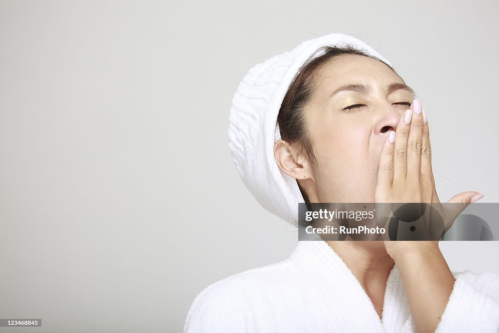 Yawning young woman in bathrobe
