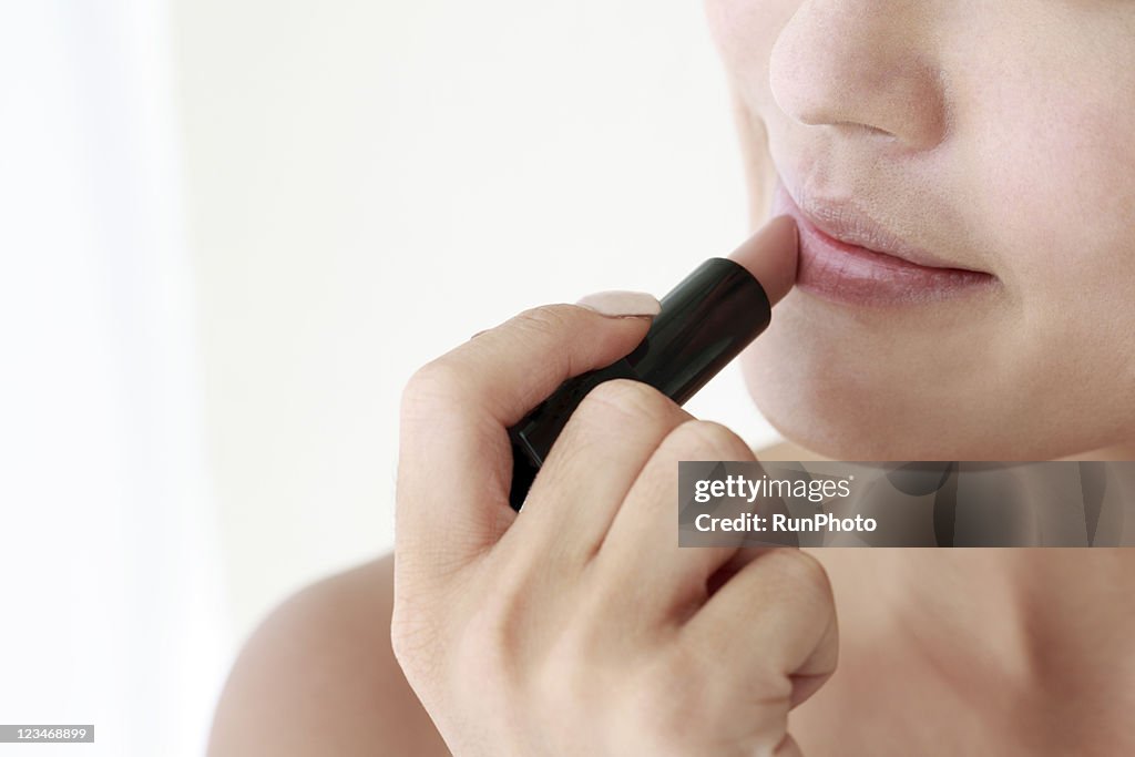 Young woman applying lipstick,close-up,beauty care