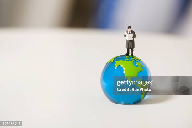 small businessman on the globe - paperweight stock pictures, royalty-free photos & images