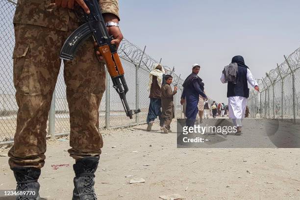 Pakistani soldier stands guard as stranded Afghan nationals return to Afghanistan at the Pakistan-Afghanistan border crossing point in Chaman on...