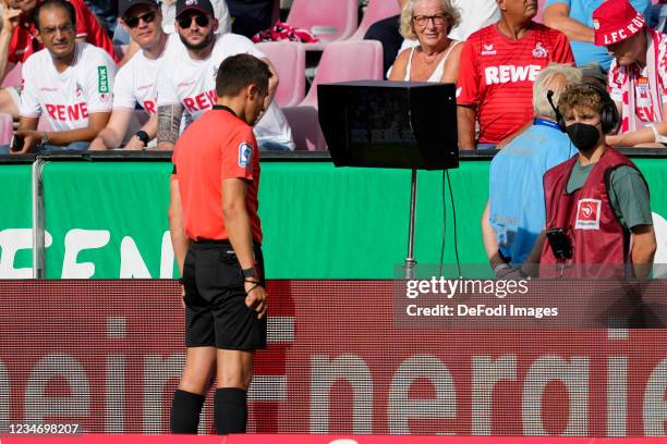 Referee Robert Hartmann looks at VAR during the Bundesliga match between 1. FC Koeln and Hertha BSC at RheinEnergieStadion on August 15, 2021 in...