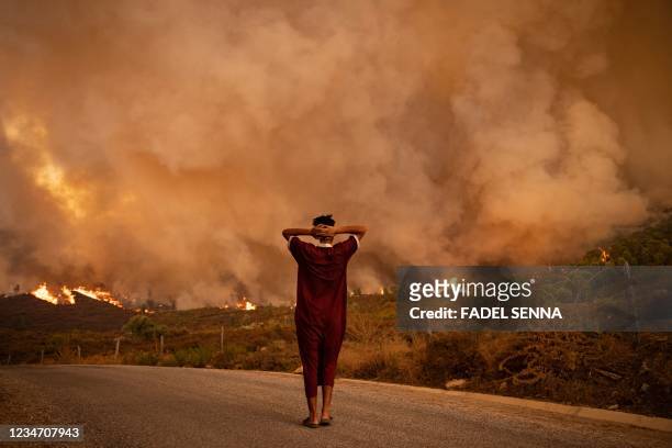Woman looks at wildfires tearing through a forest in the region of Chefchaouen in northern Morocco on August 15, 2021. - Firefighters were battling...