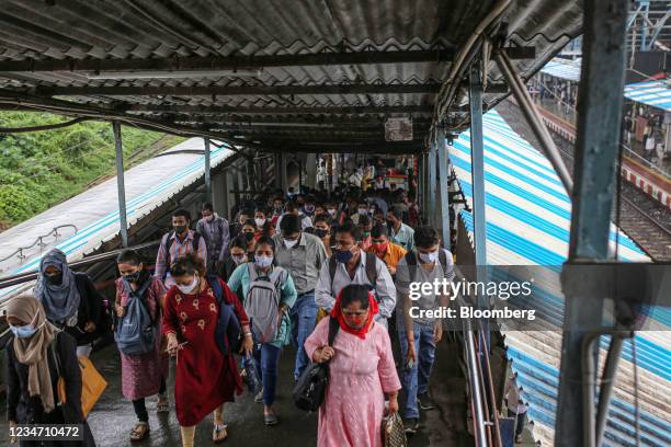 Passengers walk up a pedestrian bridge at Kurla railway station in Mumbai, India, on Monday, Aug. 16, 2021. Mumbai has restarted commuter train...