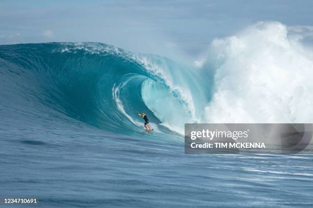 French professional surfer Justine Dupont rides a huge wave at the Teahupoo beach in the French Polynesia island of Tahiti on August 13, 2021.