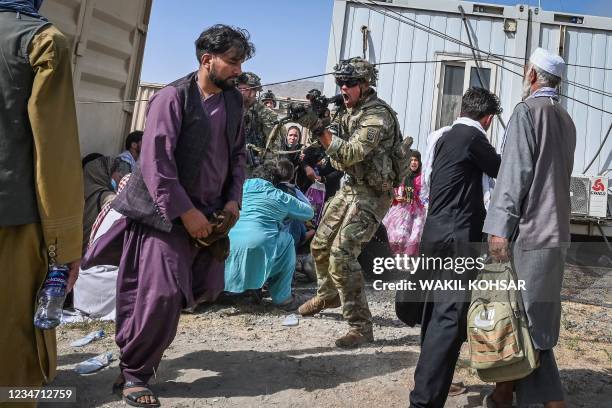 Soldier point his gun towards an Afghan passenger at the Kabul airport in Kabul on August 16 after a stunningly swift end to Afghanistan's 20-year...