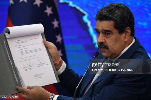 Venezuelan President Nicolas Maduro shows a document signed by representatives of the Venezuelan government and the opposition during negotiations in...