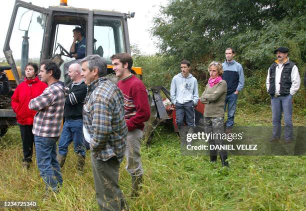 Des personnes regardent Bernard Pouey, agriculteur "bio" fauchant volontairement pour la détruire sa parcelle de maïs d'un demi-hectare "contaminée",...