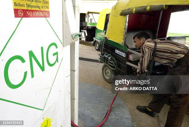 An attendent fills Compressed Natural Gas in a scooter rickshaw as others await their turn at a gas-filling station in New Delhi 27 March 2001....